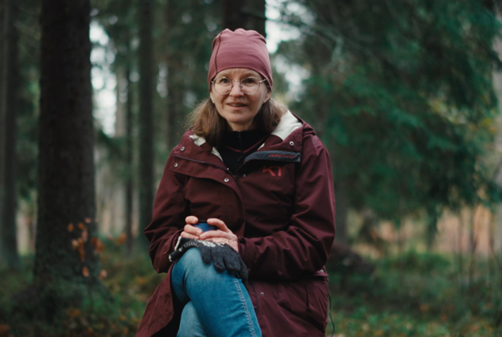 En kvinna sitter utomhus mitt i en skog